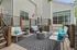 Charming outdoor deck with modern seating, vibrant cushions, and lush potted plants creating a cozy backyard retreat.
