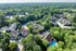 Charming aerial view of lush residential community with modern townhouses surrounded by vibrant greenery, featuring a refreshing blue swimming pool.