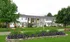 Charming townhouse complex with lush green lawns and vibrant flower beds, offering a serene suburban living experience.
