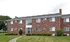 Charming brick apartment building with classic architecture, surrounded by lush green lawn and manicured shrubs.