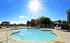 Inviting outdoor pool area with lounge chairs and umbrellas, basking under a clear blue sky.