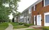 Charming row of townhouses with brick facades, surrounded by lush greenery and a welcoming pathway.