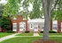 Charming townhouse with classic brick facade, vibrant green lawn, and mature trees, offering a welcoming and serene living environment.