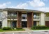 Charming apartment exterior with brick and siding facade, featuring inviting balconies and lush green landscaping.