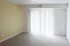 Bright and inviting living space with warm carpet flooring, neutral tones, and abundant natural light from large vertical blinds.