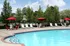 Inviting outdoor pool area with vibrant red umbrellas and ample lounge chairs, perfect for relaxation and enjoyment on a sunny day.