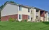 Charming suburban apartment building with modern siding and brick accents, surrounded by lush green lawn and picturesque landscaping.