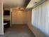 Inviting living area with plush carpet, stylish ceiling fan, and abundant natural light from vertical blinds, adjacent to a compact kitchen corner.