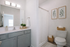 Elegant bathroom featuring a sleek modern vanity with a large mirror, stylish framed botanical prints, and cozy wicker baskets for storage.
