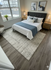 Inviting bedroom featuring a luxurious bed with plush pillows, elegant nightstands with lamps, modern artwork, and a large window with a scenic view.