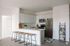 Chic modern kitchen with stainless steel appliances, white cabinetry, and a sleek island with stylish bar stools.