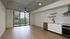 Modern open-concept apartment with sleek kitchen, hardwood floors, and floor-to-ceiling windows offering lush views.