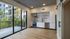 Modern kitchen with sleek white cabinetry, stainless steel appliances, and expansive floor-to-ceiling windows offering a lush garden view.