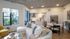Modern open-concept living space featuring a sleek kitchen with stainless steel appliances, comfy sectional with cozy decor, and large windows inviting natural light and garden views.