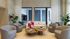Elegant living room with modern chairs, stylish coffee tables, and bright natural light from large windows.