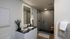 Elegant bathroom featuring a modern glass shower, sleek black countertop with double sinks, and ambient LED mirror lighting.