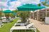 Luxurious outdoor space featuring modern sun loungers, vibrant green umbrellas, and lush greenery, perfect for relaxation and leisure.