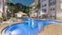 Luxurious nighttime pool view at modern apartment complex, surrounded by elegant palm trees and illuminated ambiance.