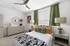 Inviting bedroom with stylish decor, featuring a bed with vibrant throw pillows, green curtains, and elegant furniture.