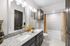 Modern bathroom featuring dual sinks, granite countertop, and a chic bathtub with patterned curtains.
