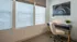 Bright and inviting home office with modern desk, chic chair, and artistic wall decor, flooded with natural light from large windows.