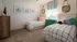 Charming kids' bedroom with twin beds featuring playful beach-themed art and vibrant pillows, ideal for a cozy and colorful space.