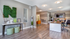 Modern office space with elegant decor, featuring sleek wood flooring, a vibrant orange chair, and lush green wall art for a stylish and inviting atmosphere.