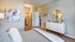 Inviting bedroom with stylish decor, plush bedding, and a modern white dresser complemented by a large round mirror.