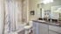 Elegant bathroom with modern fixtures, featuring a sleek granite countertop, soothing decor, and a relaxing bathtub with a floral shower curtain.