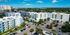Modern apartment complex with vibrant blue and green accents, lush landscaping, and ample parking, offering a welcoming and convenient living environment.