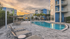 Luxurious apartment complex with a sparkling pool, stylish lounge chairs, and vibrant sunset views.