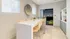 Modern kitchen area with a sleek white breakfast bar, chic wooden chairs, and stylish decor, exuding contemporary elegance and inviting ambiance.