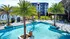 Luxurious apartment complex with a stunning outdoor pool, palm trees, and modern architecture, offering a perfect blend of relaxation and style.