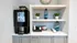 Contemporary coffee station with sleek coffee machine, modern shelving, and chic decor accents, ideal for a stylish start to your day.