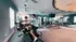Modern fitness center with natural lighting, featuring exercise bikes, weight machines, and stylish ceiling design.