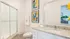 Sleek bathroom with glass shower, elegant granite countertop, and modern abstract art.