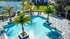 Luxurious apartment oasis featuring a sparkling pool surrounded by palm trees and stylish lounge chairs, ideal for relaxing in a serene setting.