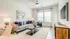 Bright living room with modern decor, featuring a cozy gray sofa, vibrant pillows, and stylish artwork. Natural light flows through large windows, highlighting a sleek coffee table and elegant furnishings.