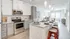 Modern open-concept kitchen with sleek gray cabinetry, stainless steel appliances, and a stylish breakfast bar leading to a bright living area.