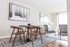Elegant modern apartment interior with stylish wooden dining set and contemporary art, featuring a cozy living area with plush seating and ample natural light.