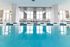 Luxurious indoor pool area with modern lounge chairs and expansive windows offering stunning city views.