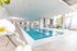 Luxurious indoor swimming pool area with modern design, featuring elegant lounge chairs, large windows, and vibrant greenery.
