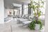 Luxurious indoor poolside lounge with sleek chaise loungers, vibrant greenery, and large windows providing natural light.