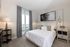 Elegant bedroom with plush bedding, modern decor, and a cozy balcony view, perfect for relaxation and comfort.