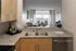 Modern kitchen view overlooking a stylish living room with floor-to-ceiling windows showcasing a scenic cityscape.