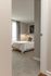 Inviting bedroom with plush carpet and elegant decor, featuring a cozy bed, stylish artwork, and a window for natural light.
