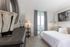 Elegant bedroom with plush white bedding, modern decor, and a private balcony offering scenic views.
