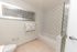 Elegant bathroom with contemporary decor, featuring checkered tile design, a modern bathtub, and tasteful wall art.