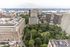 Breathtaking aerial view of a vibrant cityscape with lush greenery, majestic high-rise buildings, and a scenic river backdrop, capturing the essence of urban living.