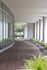 Inviting covered walkway with sleek glass windows and lush greenery, blending modern architecture with natural beauty.